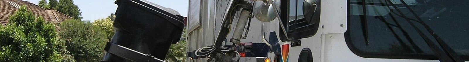 Collection truck lifting a residential waste bin at the curb